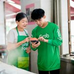 a man and woman in green shirts looking at a cell phone