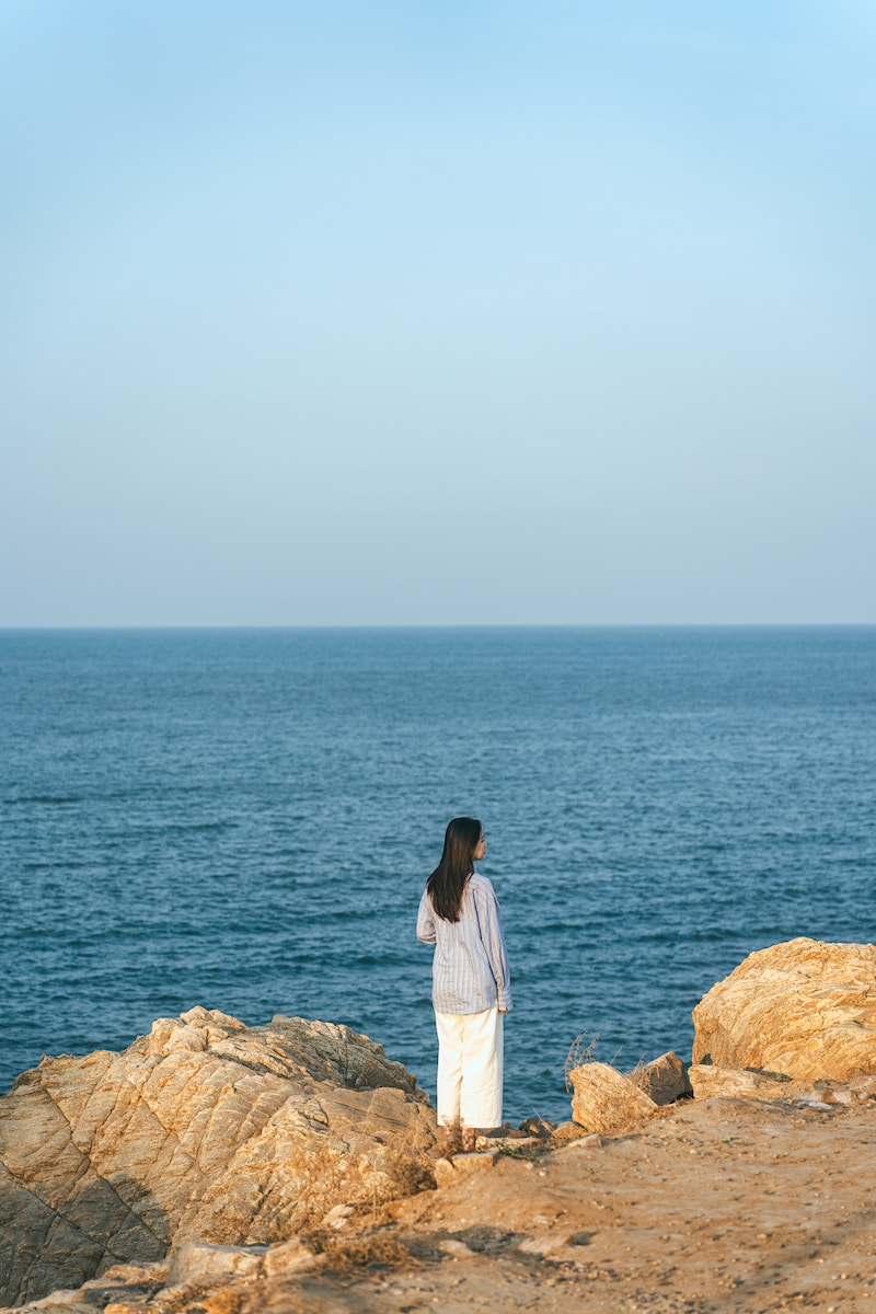a woman standing on top of a beach next to the ocean