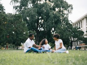 Family Sitting on Grass Near Building