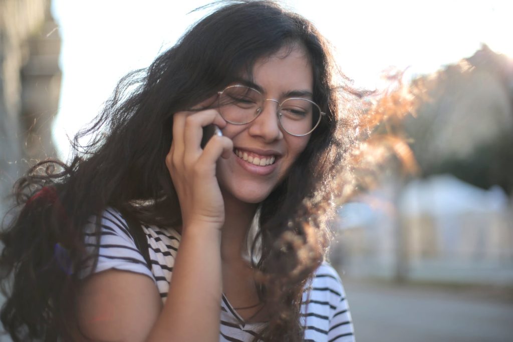 Cheerful young woman making phone call on street