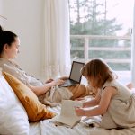 Mother working remotely while daughter drawing nearby