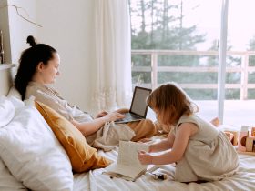 Mother working remotely while daughter drawing nearby