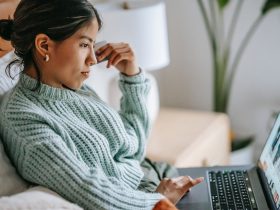 Side view of crop concentrated young ethnic female using touchpad of netbook and shopping online