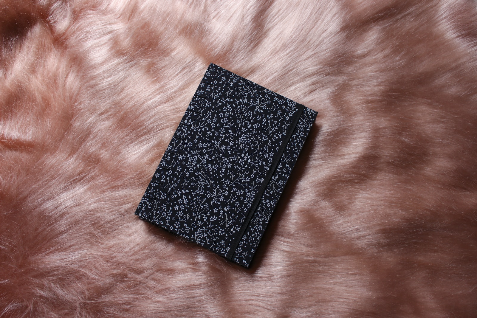 a black book sitting on top of a fur covered floor