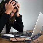 woman in black long sleeve shirt covering her face with her hands