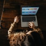 person using macbook pro on brown wooden floor