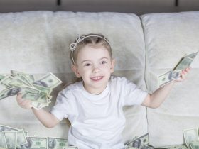 a little girl sitting on a couch holding money