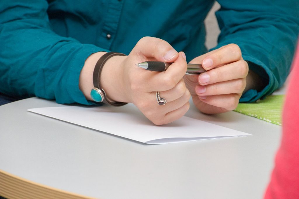 a person sitting at a table writing on a piece of paper