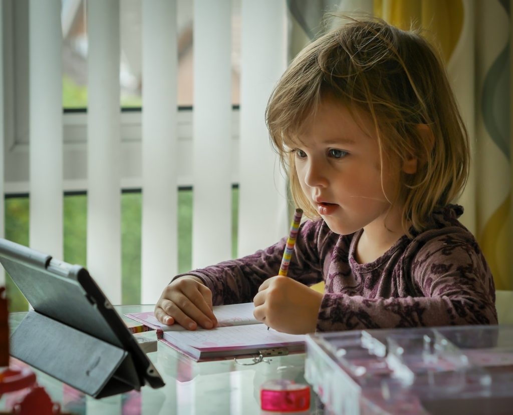 girl in purple and black long sleeve shirt holding black pen writing on white paper