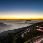 time lapse photo of car lights on mountain road during nighttime