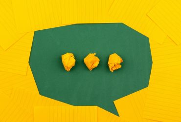 three crumpled yellow papers on green surface surrounded by yellow lined papers