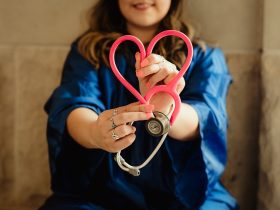 girl in blue jacket holding red and silver ring