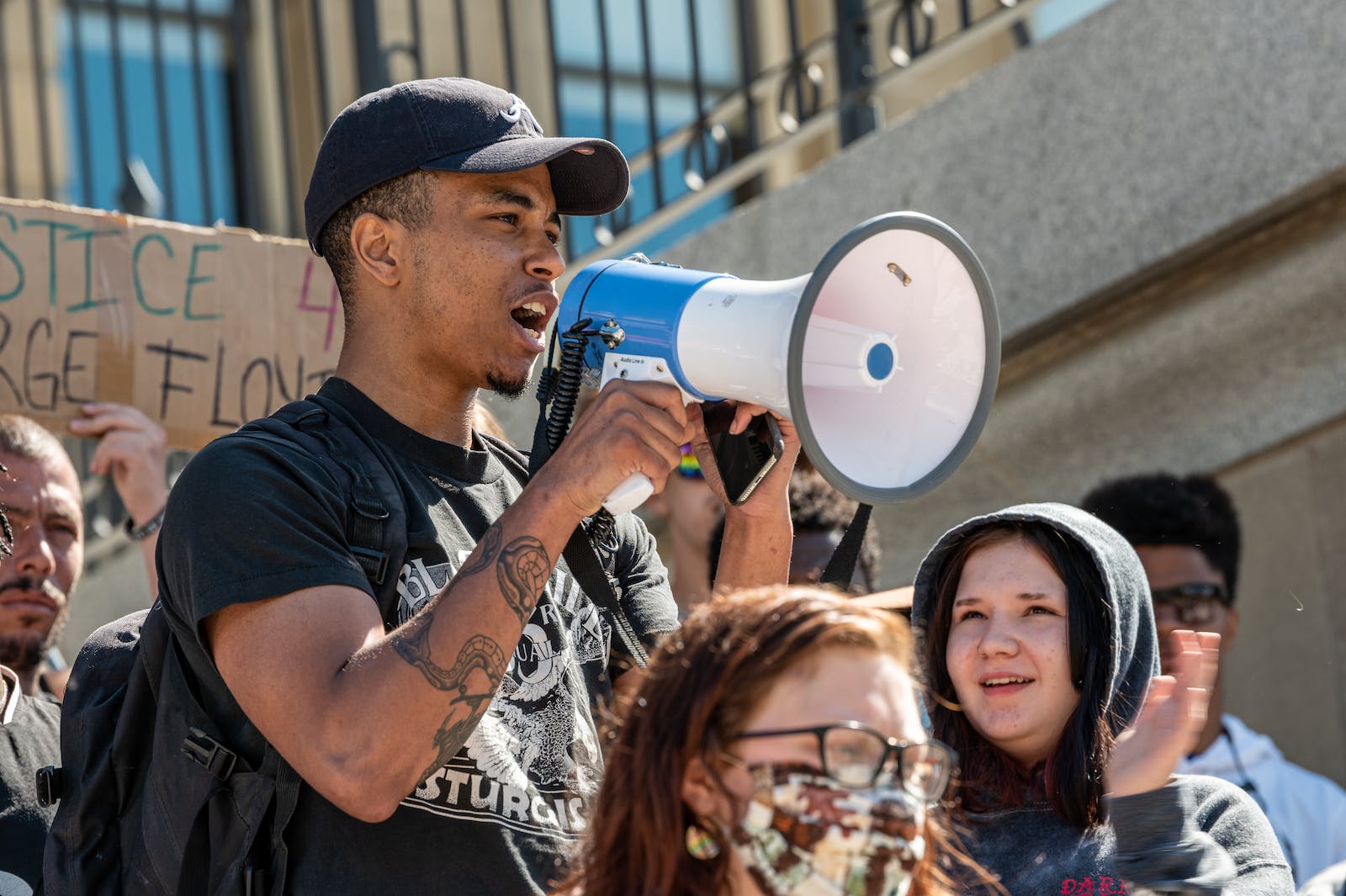 Black tattooed man speaking into loudspeaker during manifestation