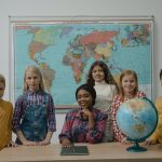 Teacher and a Group of Children Standing Beside Table With Globe
