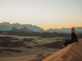 a woman sitting on top of a sand dune