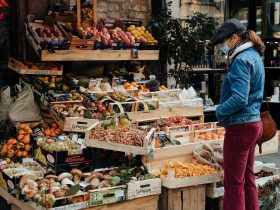 man in blue jacket standing in front of fruit stand