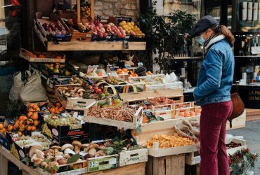 man in blue jacket standing in front of fruit stand