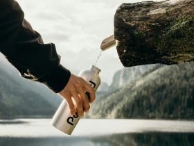 person holding gray sports bottle near nozzle