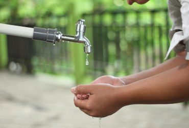 person washing hands in open faucet